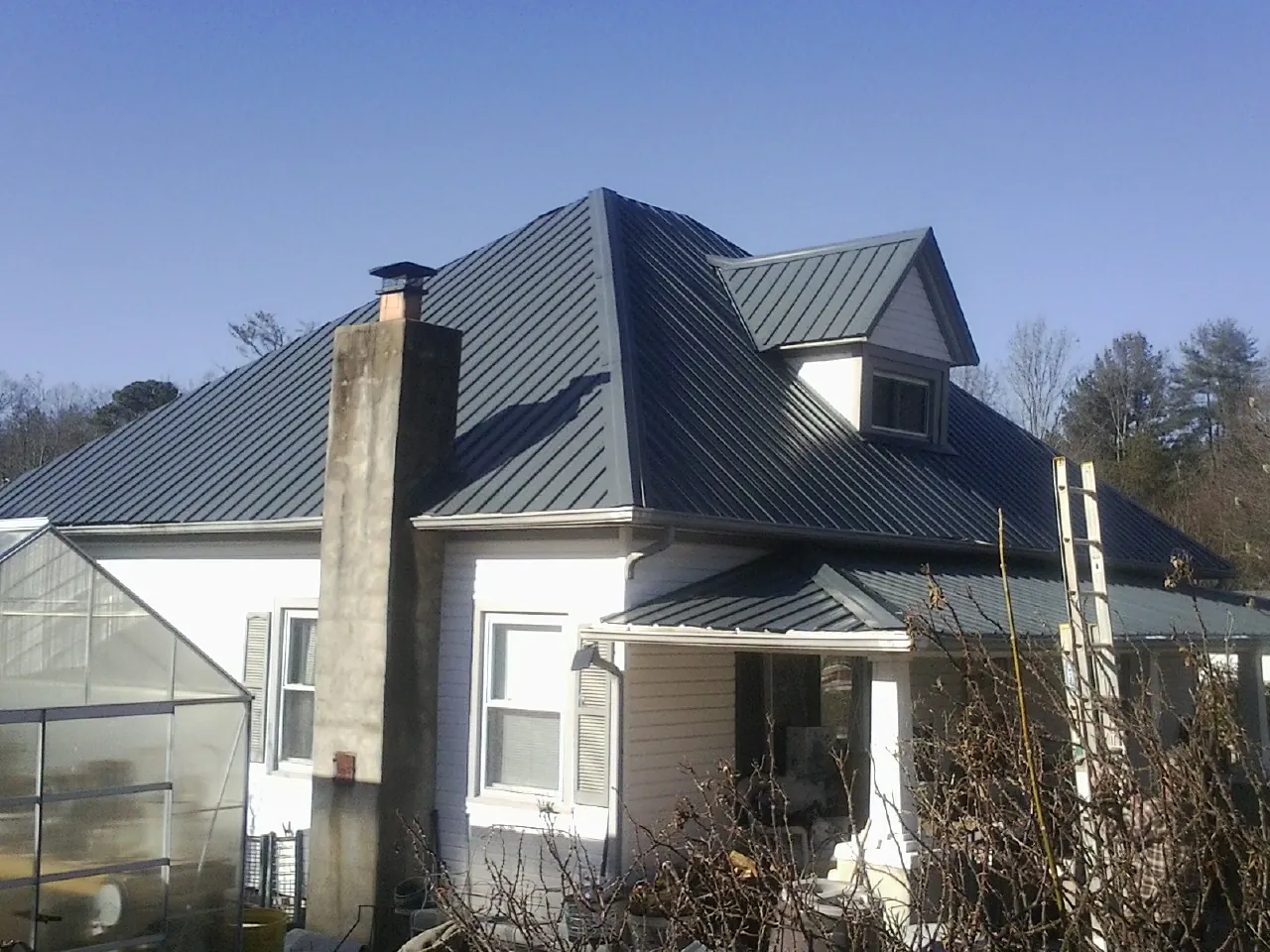 Dark blue standing seam metal roof on a white farmhouse with dormer — Slate & Tile Roof Repair by Roofing Brothers in Linden