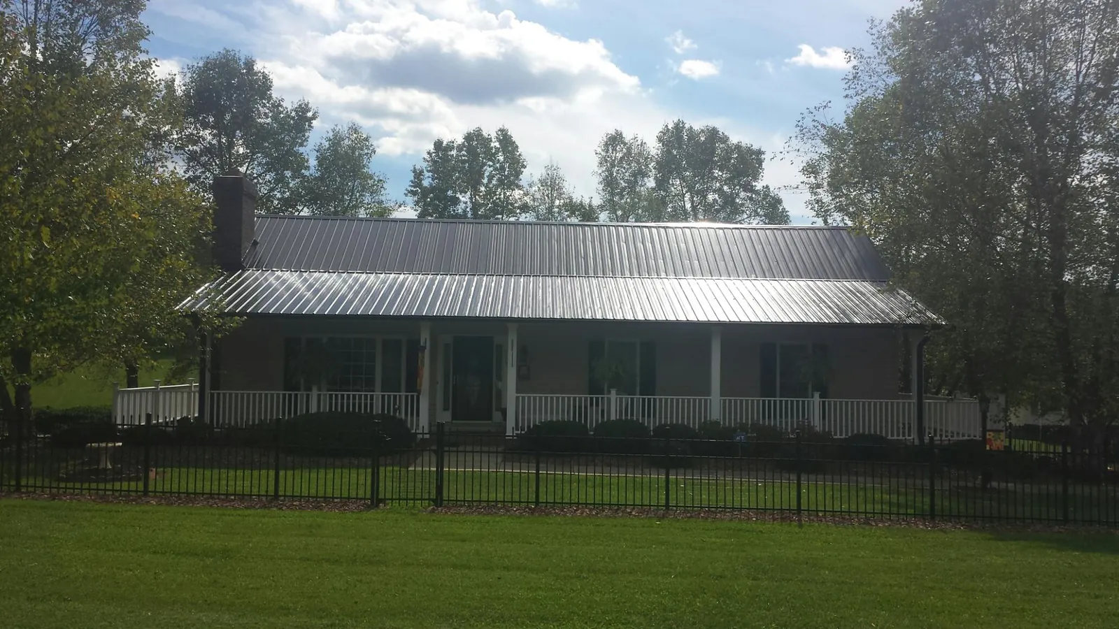 Gray metal roof on a brick ranch with a full width front porch — Gutter Guard Installation work by our crew in Linden